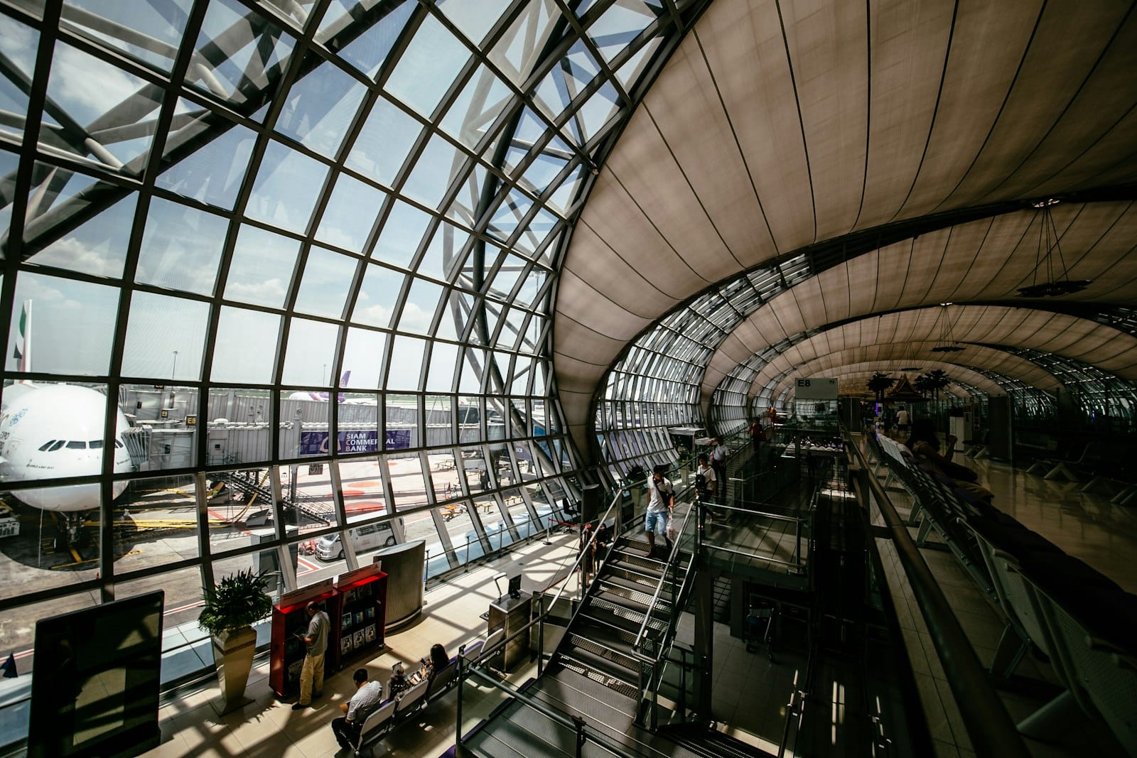 Passengers moving through a glass-roofed airport terminal